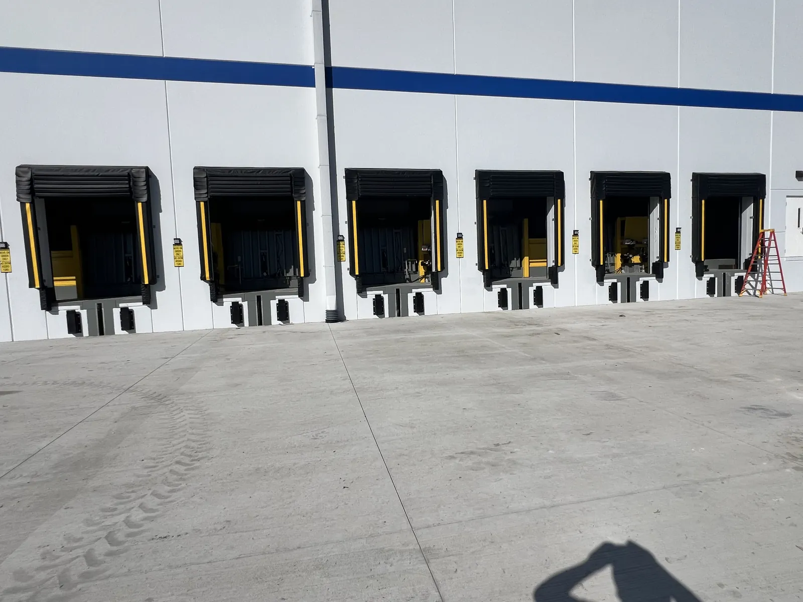 Interior row of loading dock positions with hydraulic levelers, compression seals and yellow bumpers